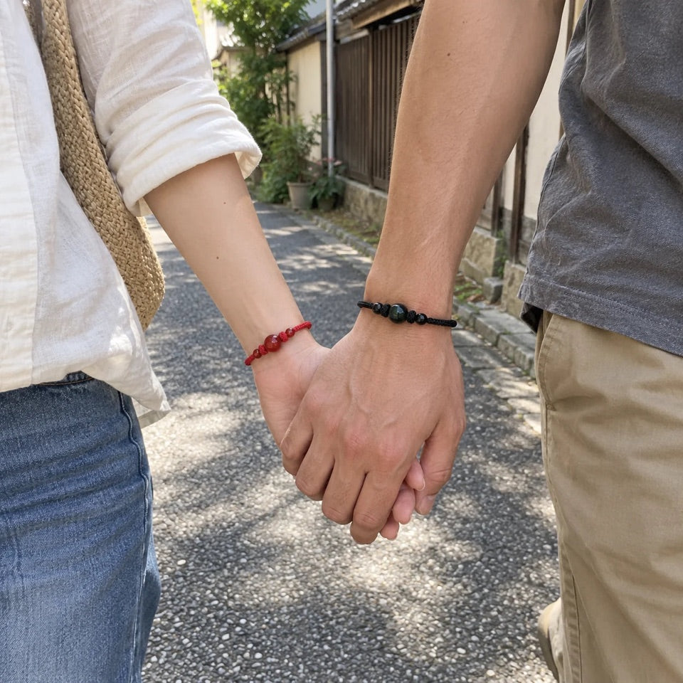 Deux personnes main dans la main avec des bracelets rouge et noir